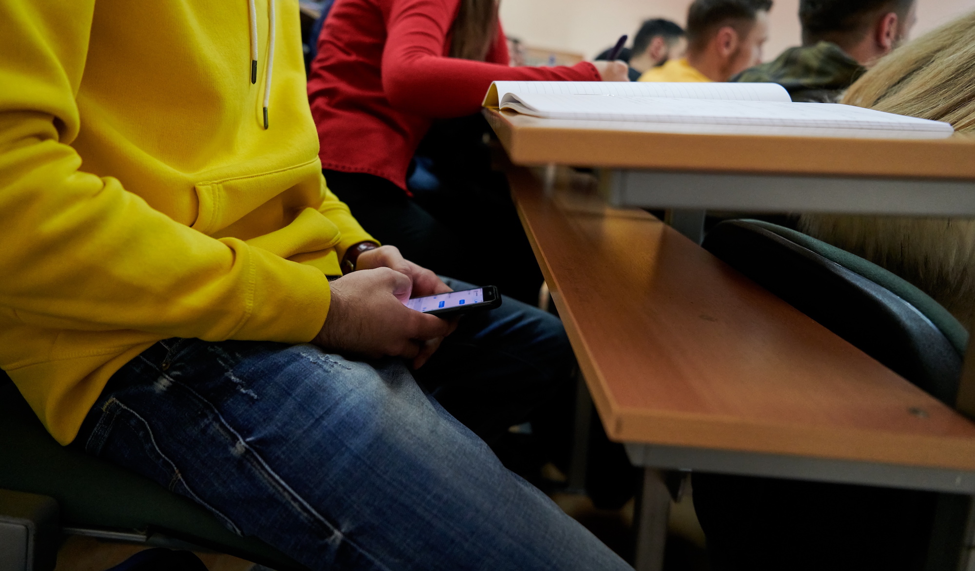 Person taking test while looking at phone under desk